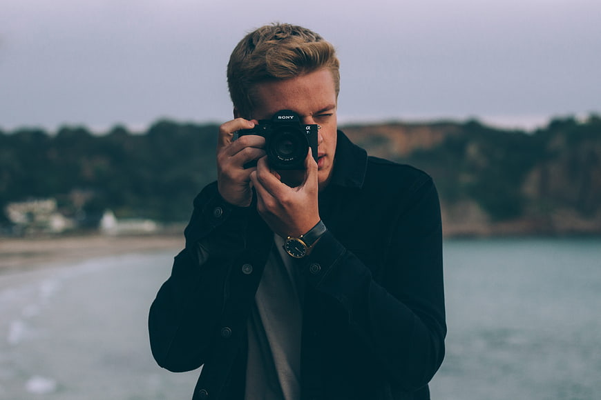 Male Photographer Taking Photo on Beach with Camera