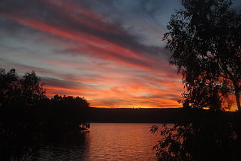 Dramatic Sunset Over Lake with Silhouetted Trees