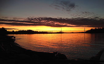 Silhouette of suspension bridge over water at sunset