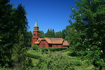 Red wooden church in Sweden surrounded by green trees