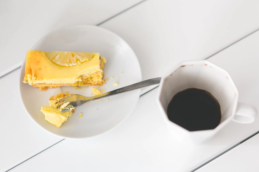 Lemon cheesecake slice with coffee on white table