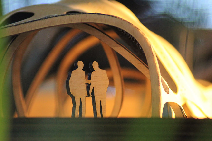 Wooden architectural model with couple silhouette inside curved structure