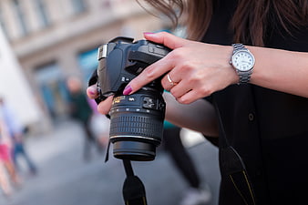 Close-up of woman holding DSLR camera with watch and ring
