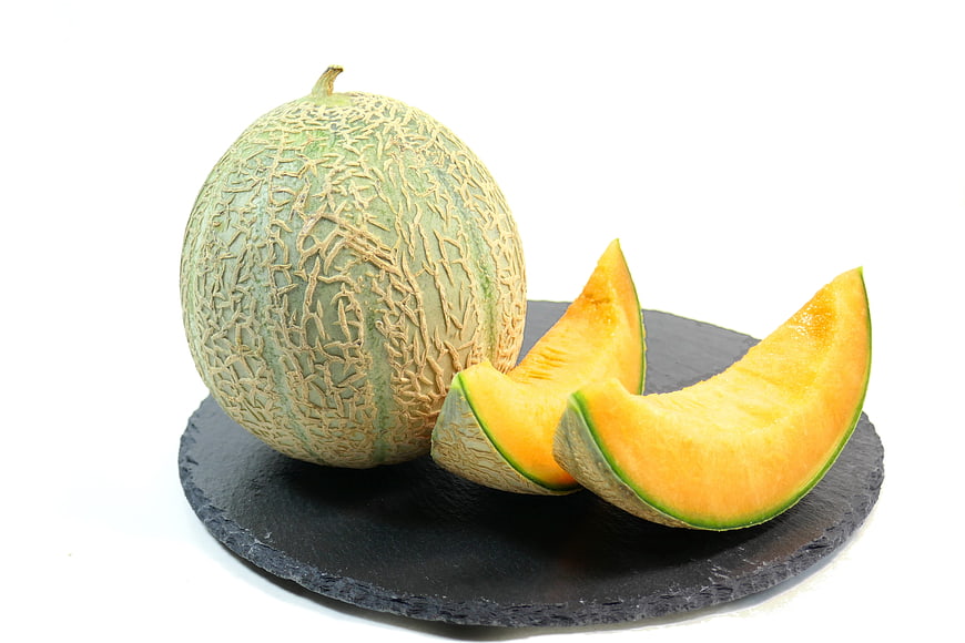 Whole Cantaloupe Melon With Slices On Black Slate