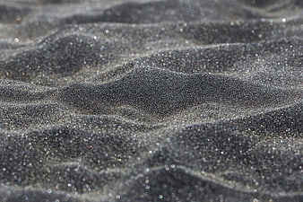 Close-up of sparkling wet black sand texture on a beach