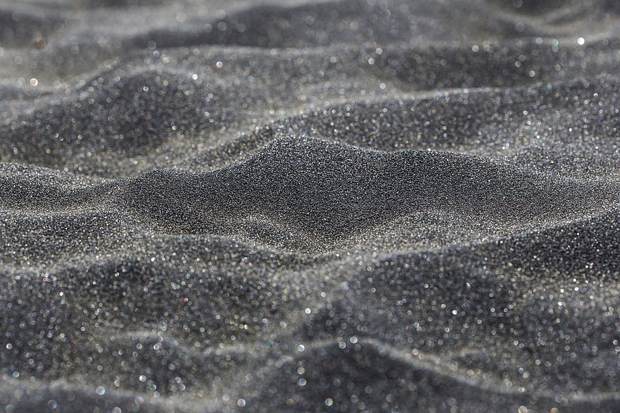 Close-up of sparkling wet black sand texture on a beach