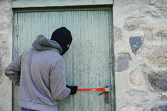Burglar with crowbar breaking into wooden door