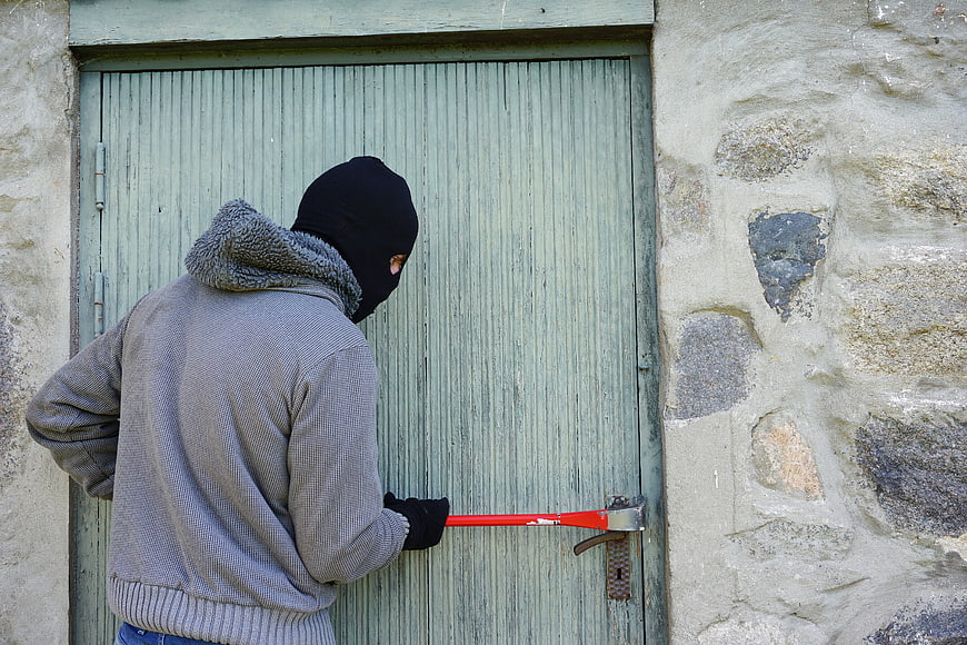 Burglar with crowbar breaking into wooden door
