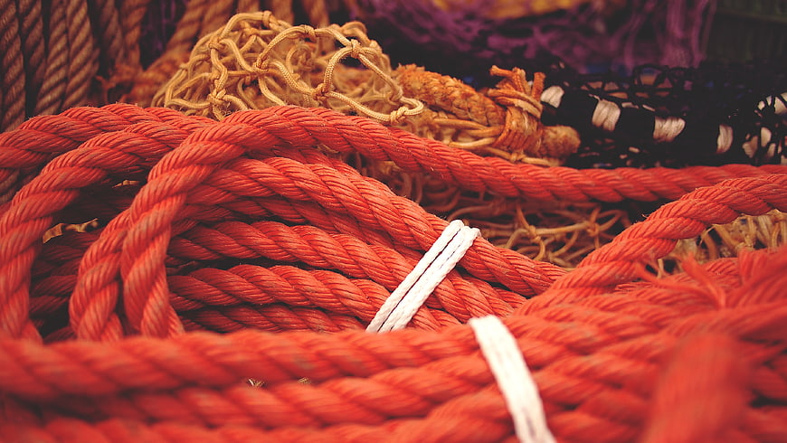 Close-up of orange nautical rope coils with white ties