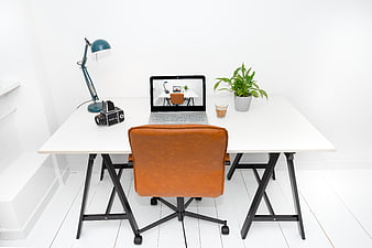 Minimalist white workspace with laptop and leather chair