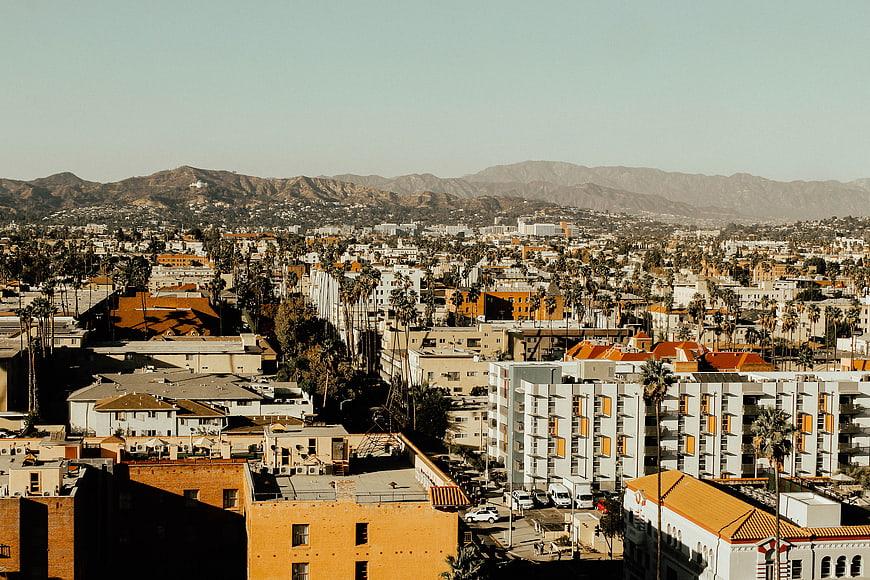 Sunlit Los Angeles Cityscape with Mountains and Palm Trees