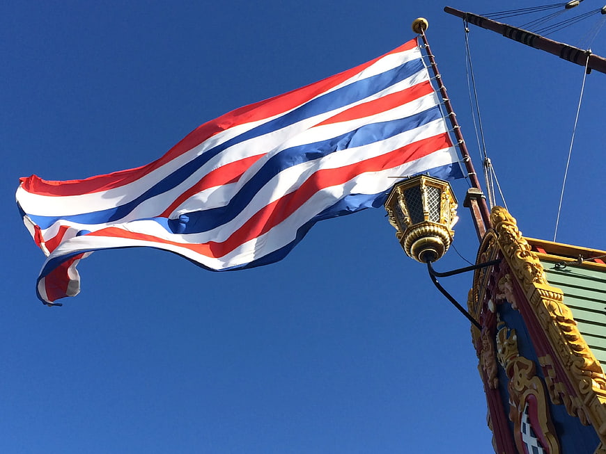 Thai flag waving against blue sky on ornate ship