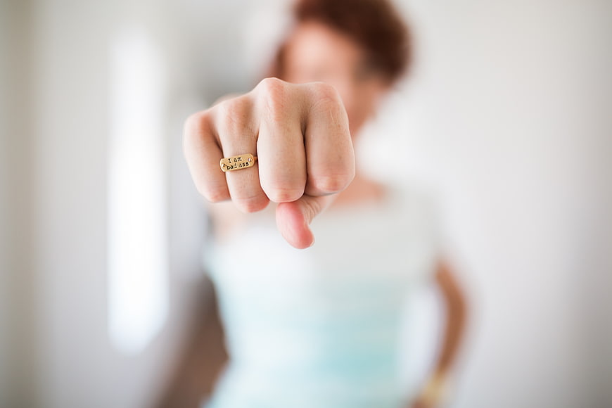 Woman showing gold ring with empowering inscription
