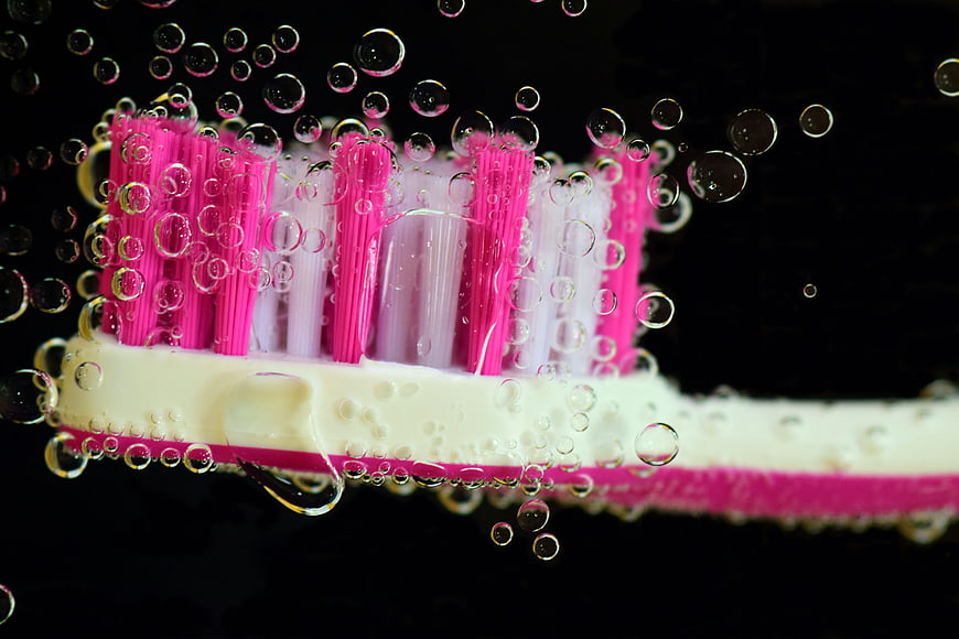 Close-up of pink and white toothbrush head underwater with bubbles