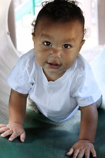 Cute baby crawling on green surface looking at camera