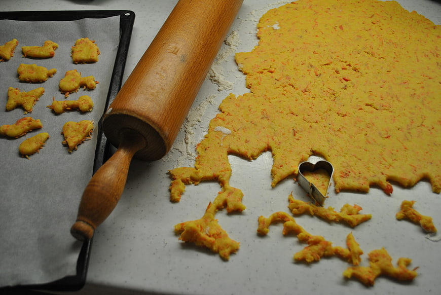 Homemade carrot cookie dough preparation with rolling pin
