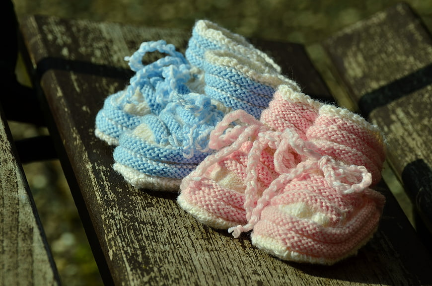 Hand-knitted pink and blue baby booties on rustic wood