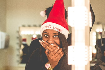 Surprised Black Woman in Santa Hat Looking in Mirror