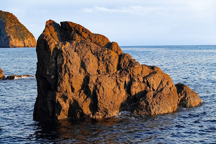 Sunlit Rock Formation in Calm Blue Sea
