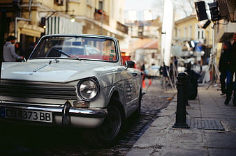 Vintage White Car Parked on Cobblestone Street