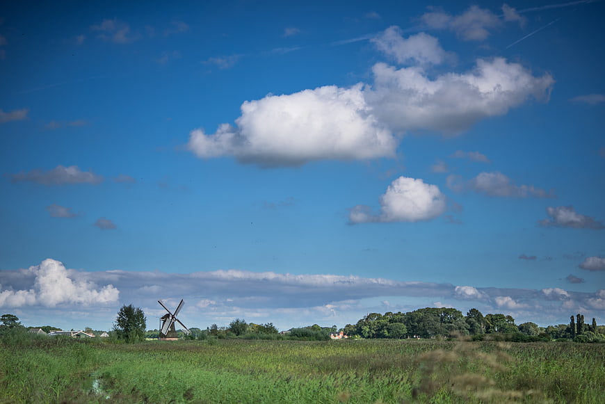 Traditional Dutch windmill in green meadow under blue sky