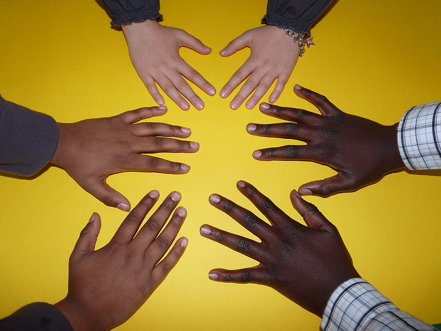 Diverse Hands Together on Yellow Background Symbolizing Unity