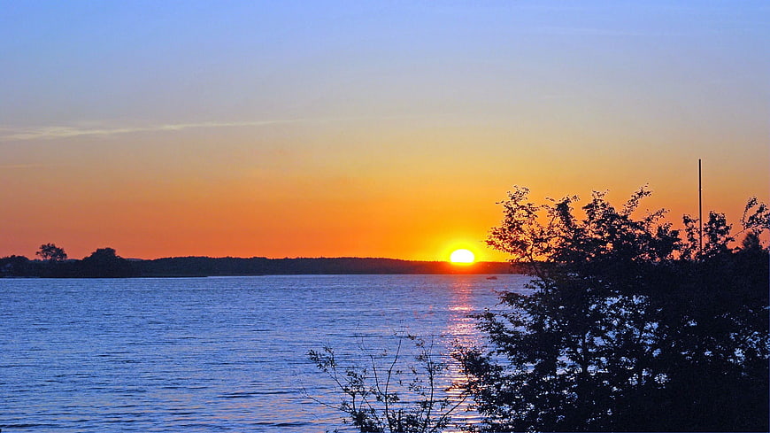 Serene Sunset Over Lake with Silhouetted Trees