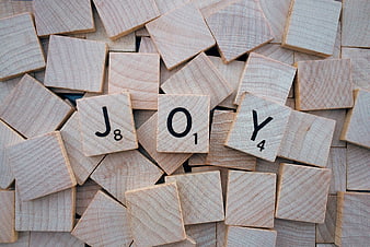 Wooden Scrabble Tiles Spelling Joy on Pile