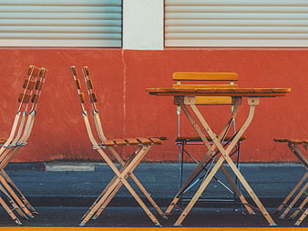 Empty wooden cafe chairs and table against red wall