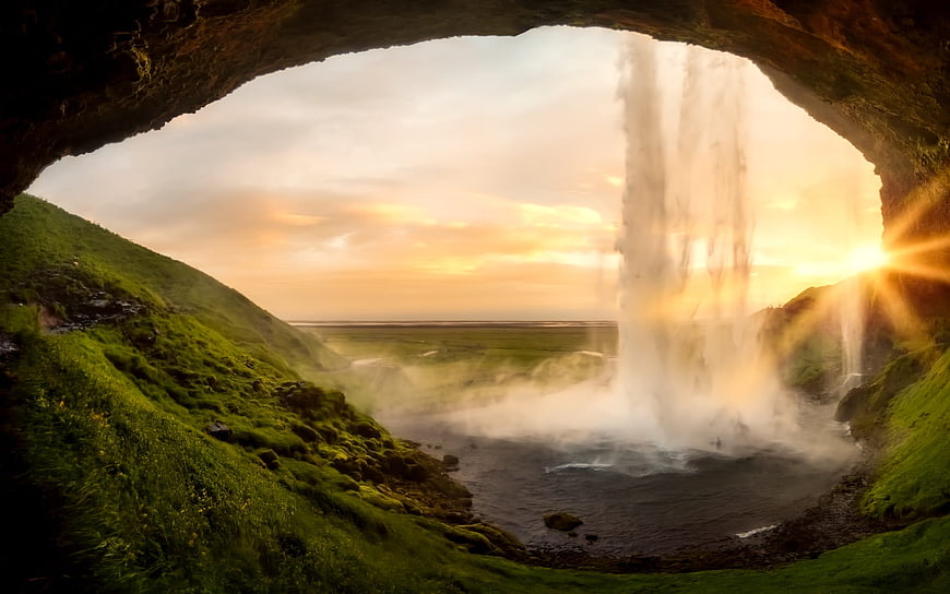 Sunset View of Seljalandsfoss Waterfall Through Cave Arch