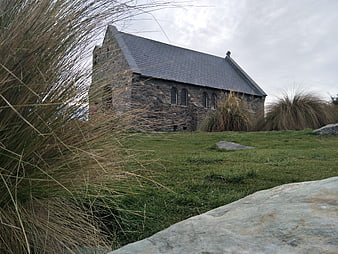 Old stone church on grassy hill with tall grass foreground
