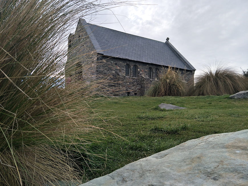 Old stone church on grassy hill with tall grass foreground