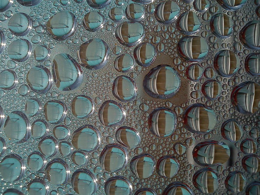 Macro water droplets on glass with blue and brown reflections