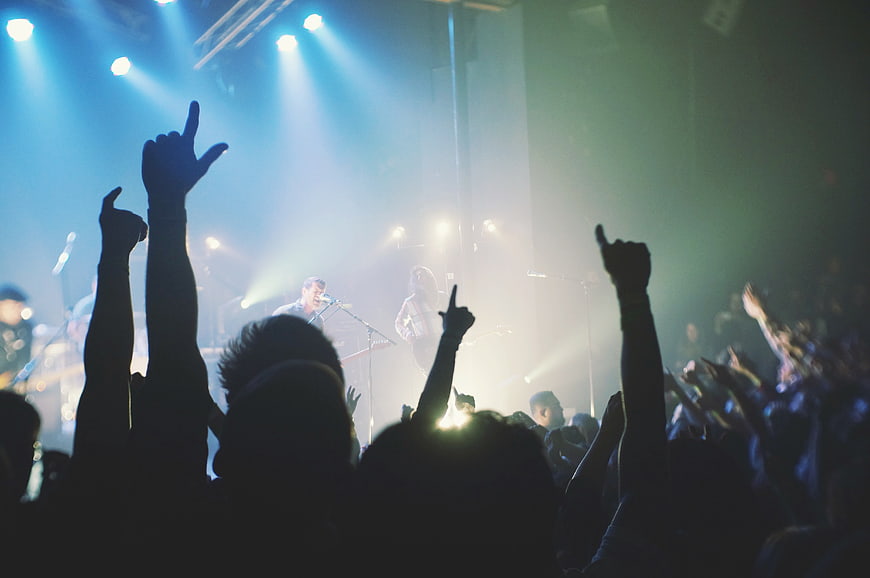 Silhouetted crowd cheering at a live rock concert with stage lights