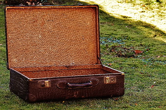Open vintage leather suitcase on green grass