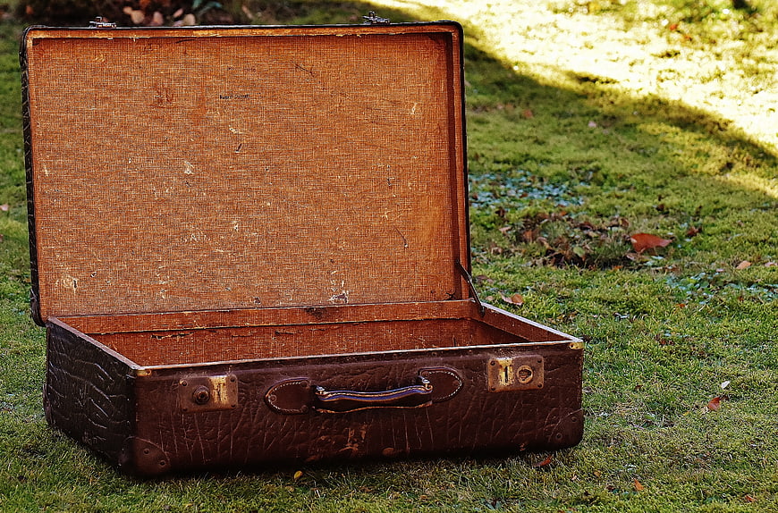 Open vintage leather suitcase on green grass