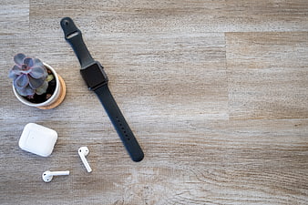 Flat lay of smartwatch, wireless earbuds, and succulent on wood