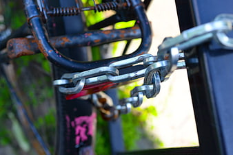 Close-up of rusty bicycle secured with heavy metal chain lock