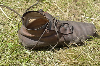 Old worn leather shoe lying in dry grass