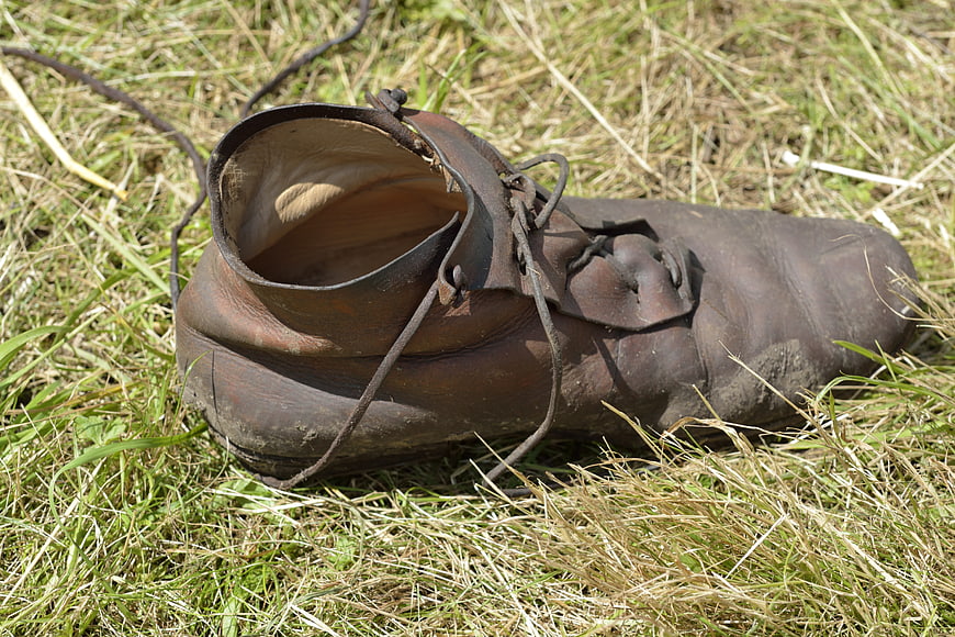 Old worn leather shoe lying in dry grass
