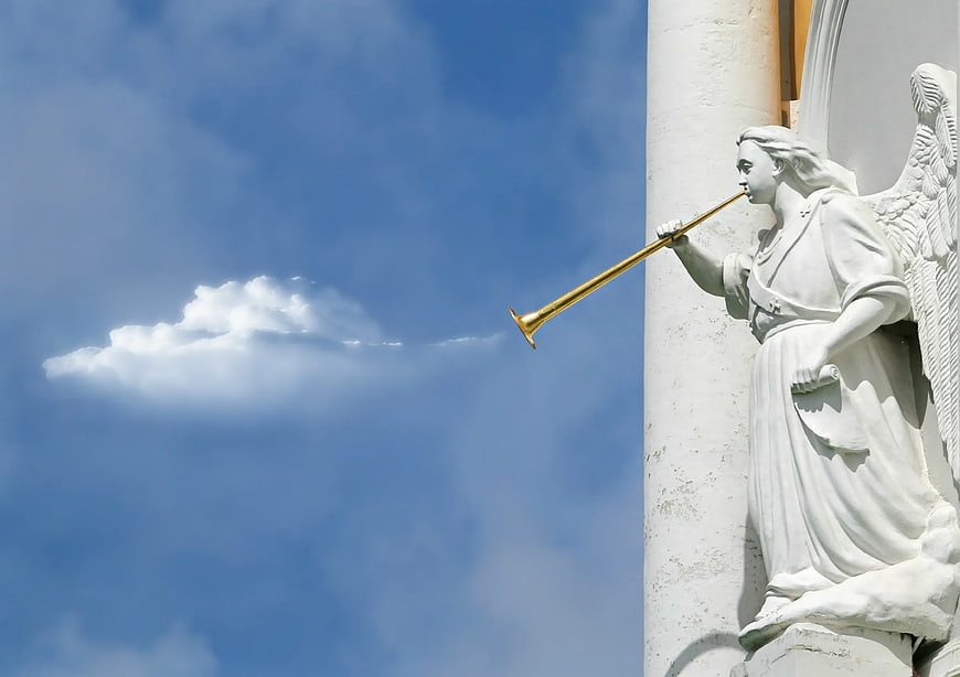 White Angel Statue Blowing Golden Trumpet Against Blue Sky