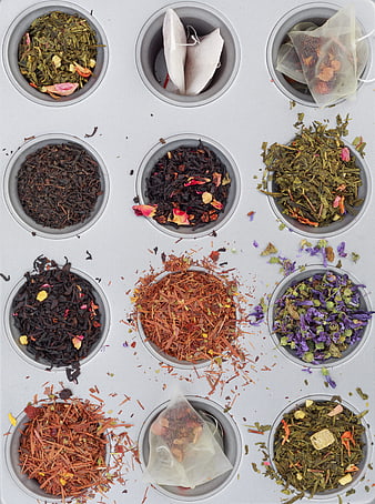 Flat lay of various loose leaf teas and tea bags in metal cups