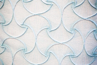 Close-up of white fabric with blue scalloped embroidery pattern