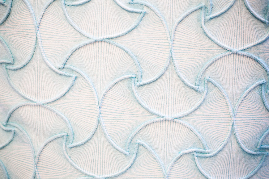 Close-up of white fabric with blue scalloped embroidery pattern