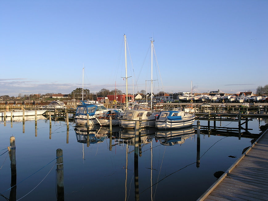 Sailboats docked in calm harbor with reflections