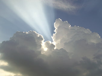 Dramatic Sunbeams Breaking Through Clouds in Blue Sky