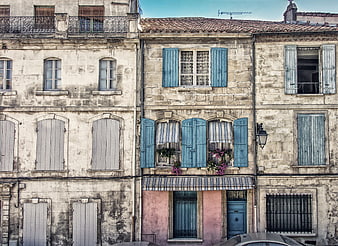 Old European building facade with blue shutters and flowers