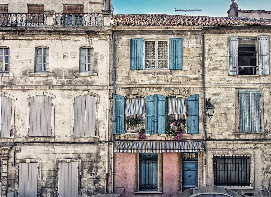 Old European building facade with blue shutters and flowers