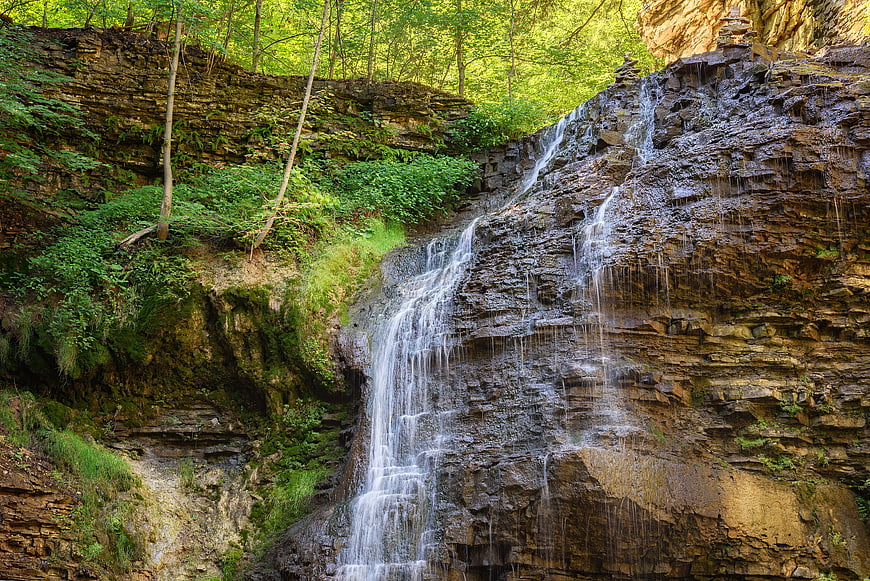 Waterfall cascading down rocky cliff in lush green forest