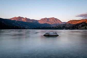 Serene Lake Landscape with Misty Water and Sunlit Mountains